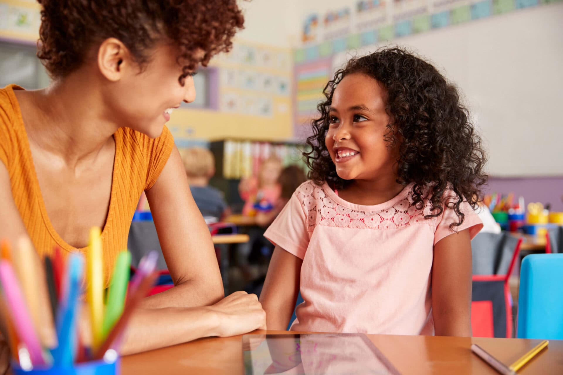 A teacher and a child smiling at each other in a Creation Kingdom classroom